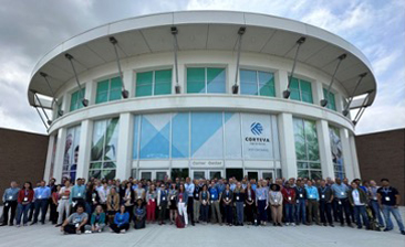 Large group of people standing in front of the Corteva Agriscience building, posing for a group photo during an event or conference.