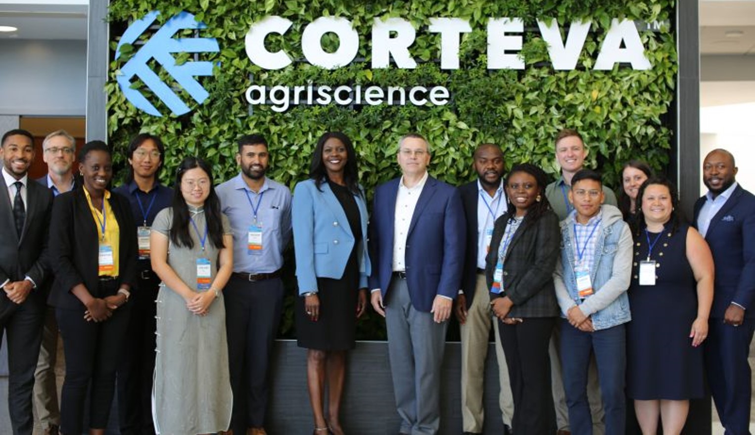 Group of professionals standing in front of a green wall with the Corteva Agriscience logo, posing for a group photo at an event or conference.