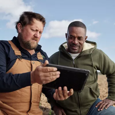 two men in field viewing data on tablet