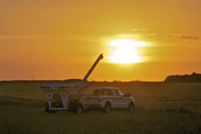 pickup truck in field at sunset with orange sky