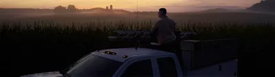 Man standing in truck during sunset